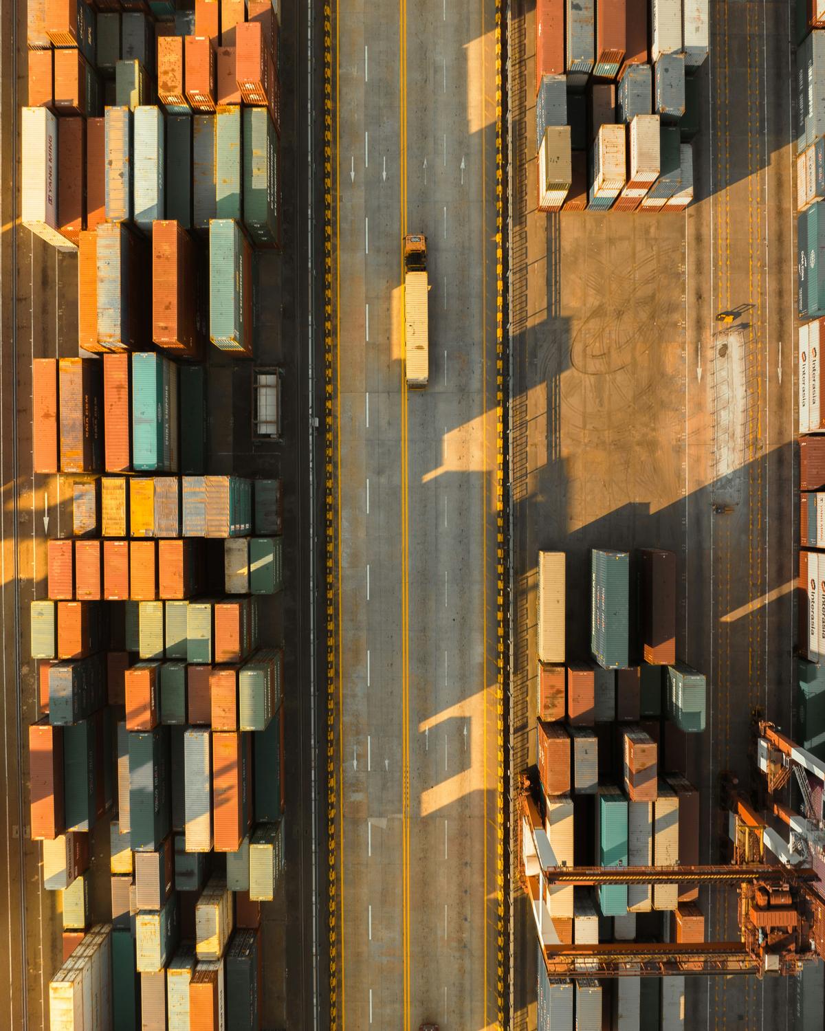 Aerial view of a container yard at a port, with stacks of containers either side of a haul road